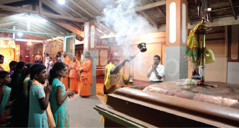 The puja at the shrine dedicated to Palani Murugan. The priest is paying his respects to the vel embedded